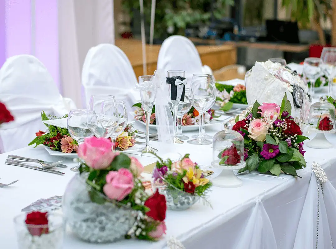A table set with white chairs and flowers.